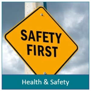 Picture of a pole with a yellow diamond shaped sign with the words Safety First. Under the picture it says Health and Safety